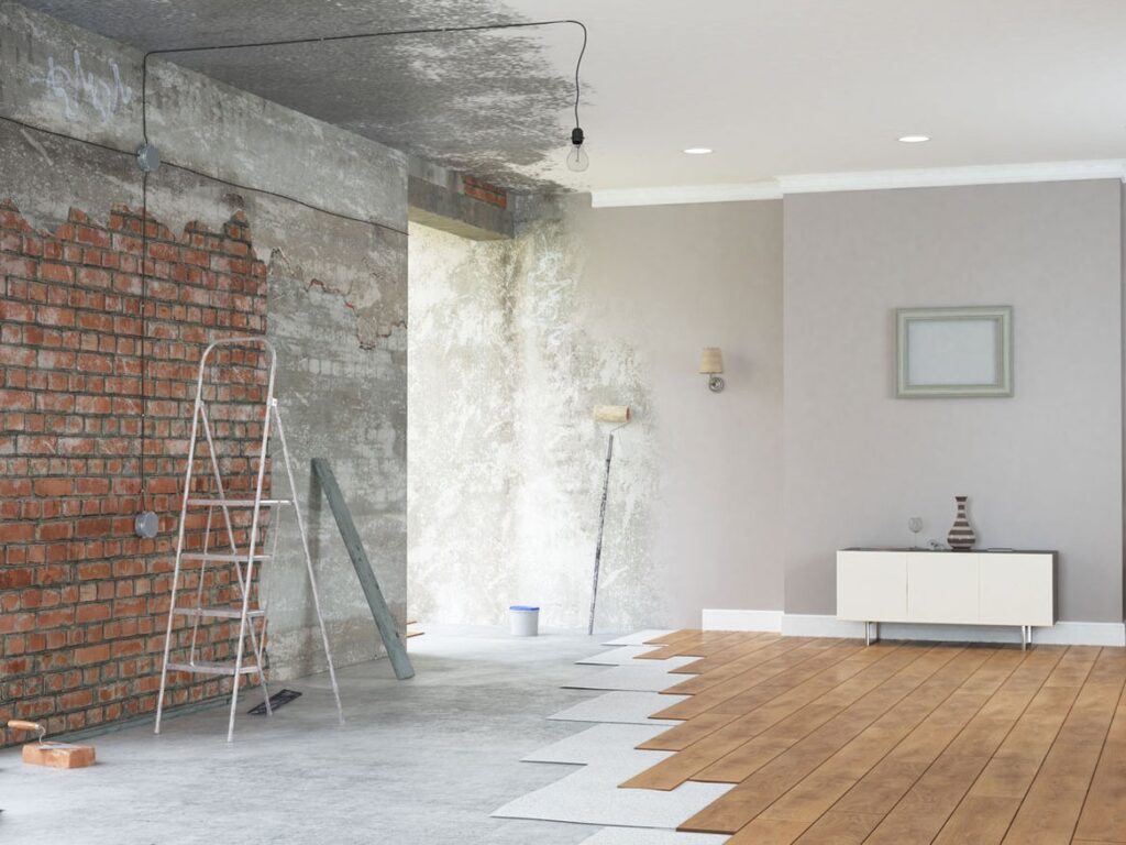 Interior renovation scene with partially removed drywall and exposed brick wall.