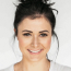 Centered portrait of a woman with tied-back dark hair.