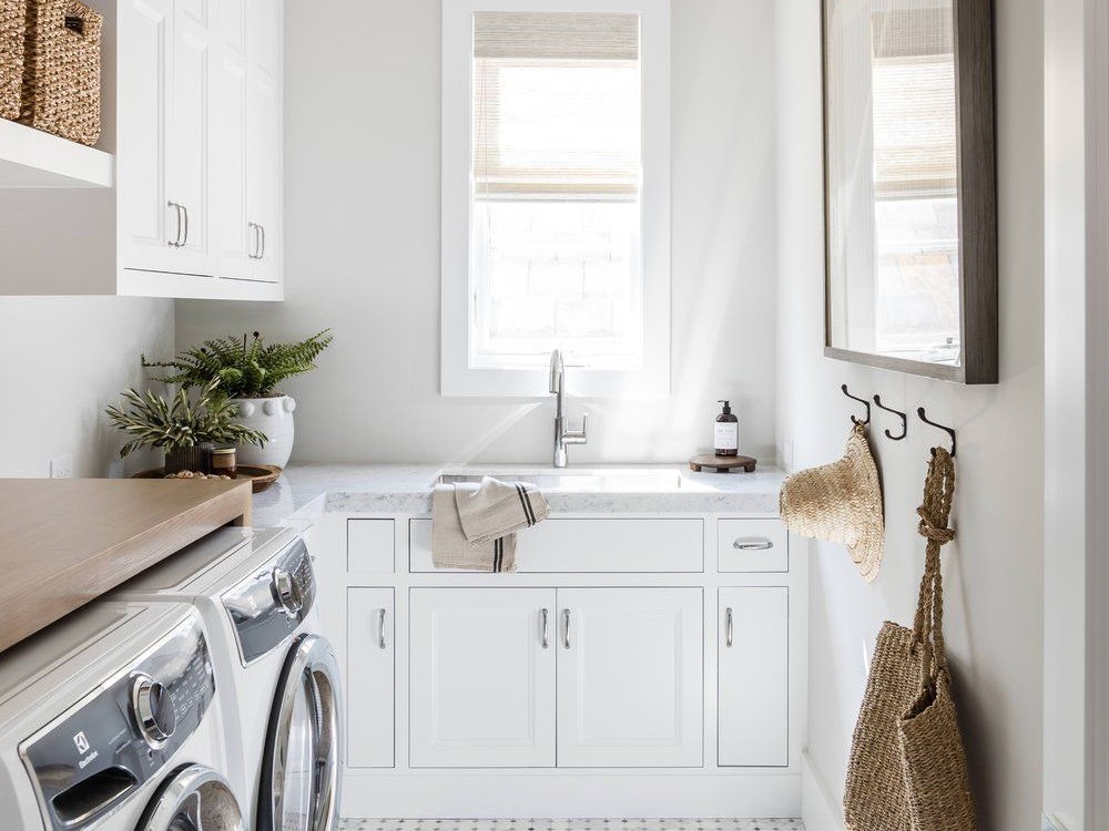 Bright laundry area with white cabinets, hanging apron, and natural light.