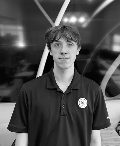 Black-and-white headshot of a smiling man wearing a branded polo shirt