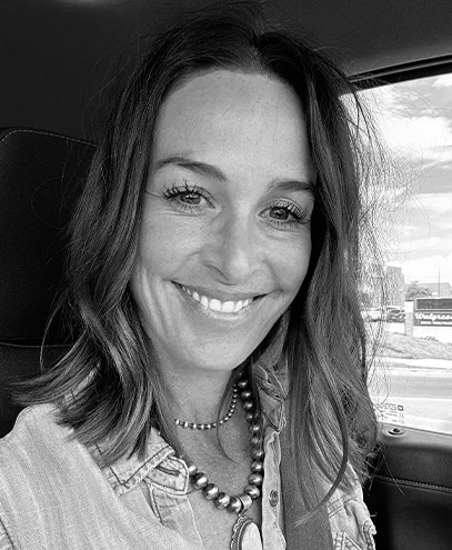 Casual headshot of smiling woman sitting in a car, wearing a necklace.