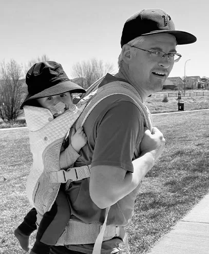 Man carrying baby in a hiking child carrier on a bright day