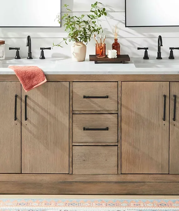 Rustic bathroom vanity with wood cabinetry, black fixtures, and a red towel accent.