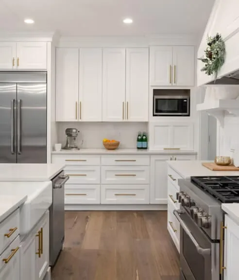 Bright white kitchen with stainless steel refrigerator, oven, and open shelving.