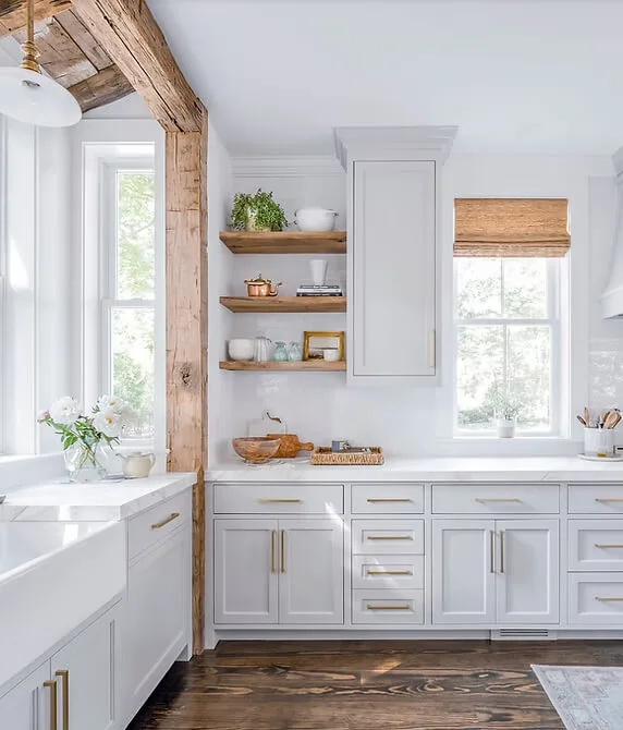 Farmhouse kitchen with white cabinets, wooden countertops, and large corner windows.