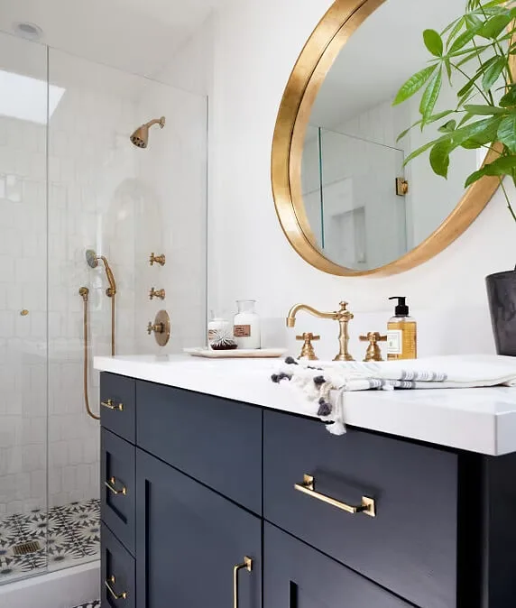 Contemporary bathroom featuring a navy vanity, gold-framed mirror, and glass shower.