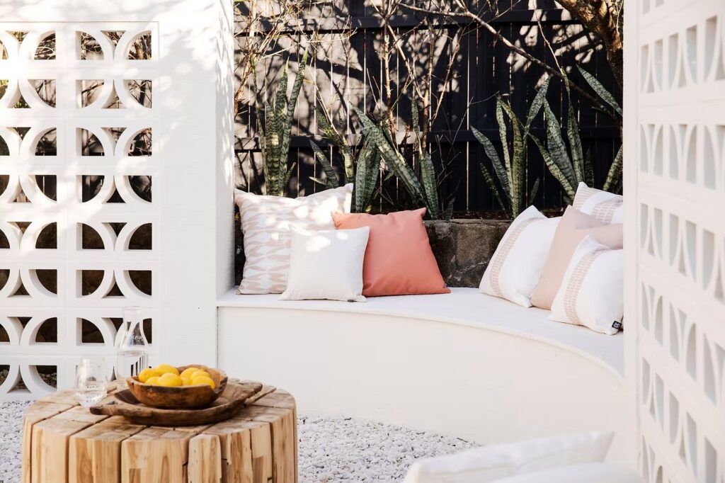 Luxurious outdoor lounge with white and peach cushions beside natural elements.