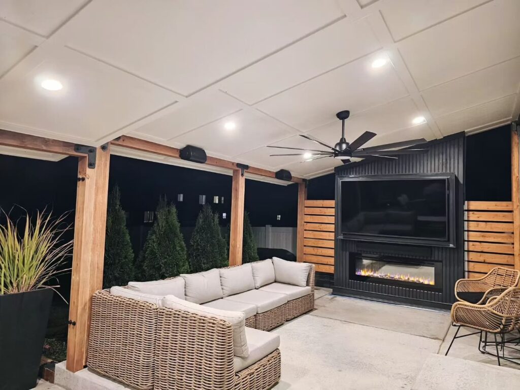 Outdoor patio seating area with sectional sofa, ceiling fan, and fireplace.