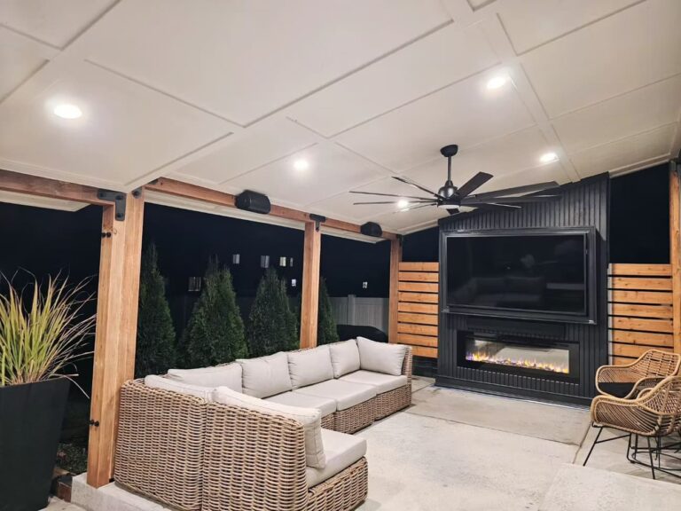 Outdoor patio seating area with sectional sofa, ceiling fan, and fireplace.