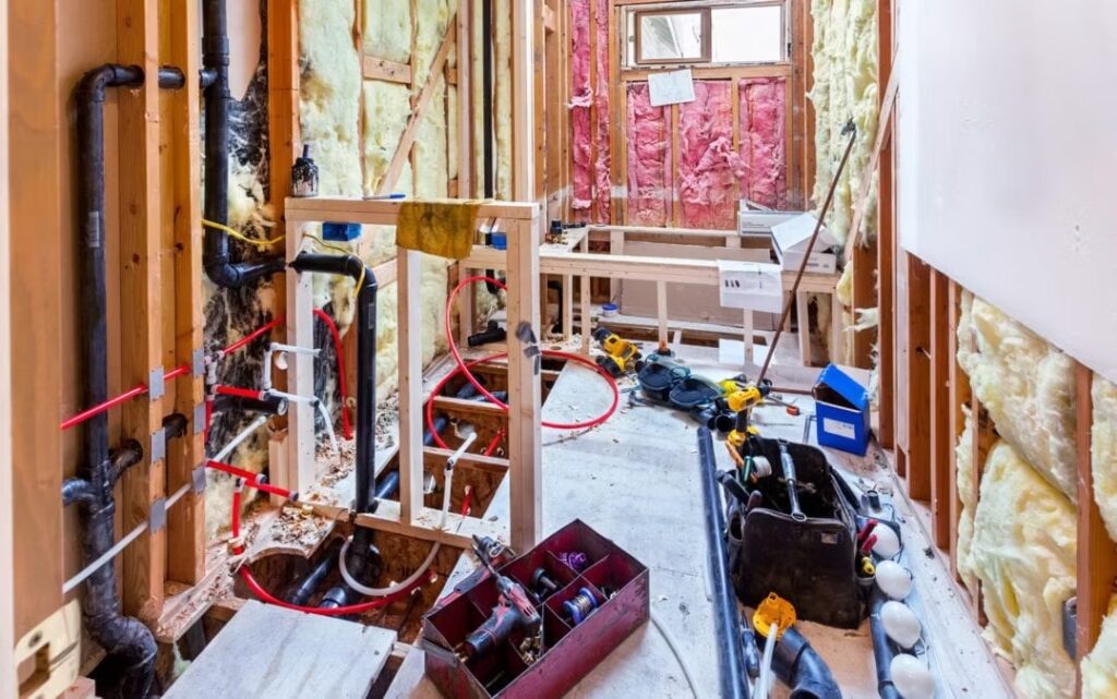 Home under construction with tools, insulation, and visible framing.
