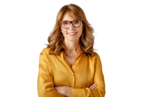 Smiling woman with glasses and mustard blouse posing against a white background.