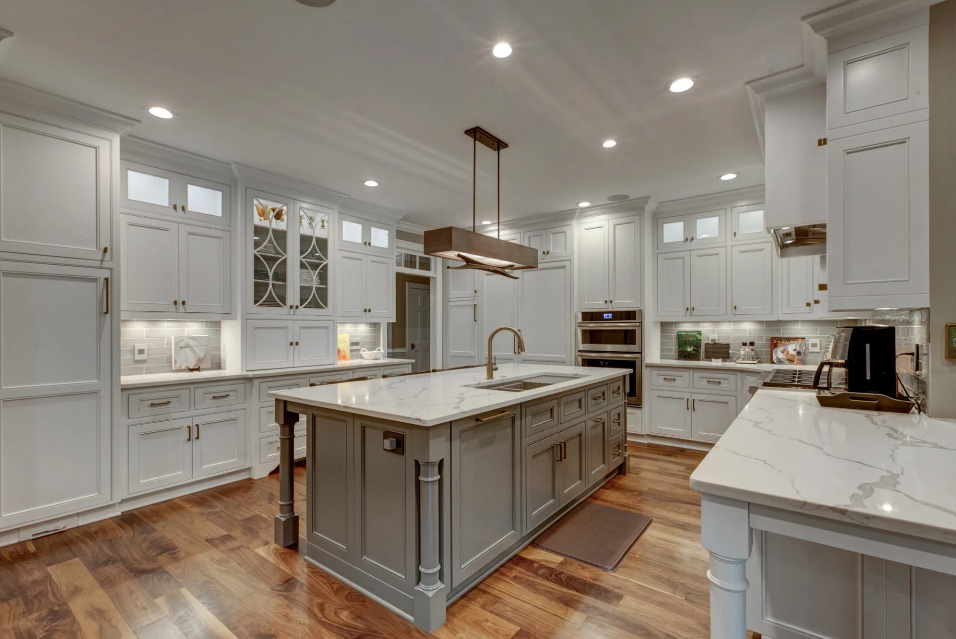 Stylish kitchen with gray cabinetry, large island, and wooden floors.