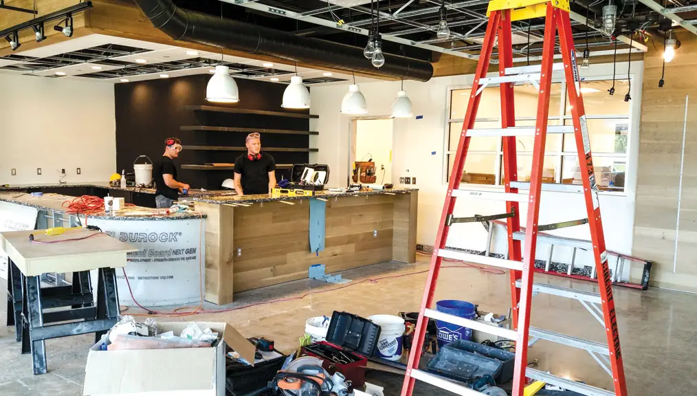 Restaurant space under renovation with tools, lighting, and exposed ceiling.