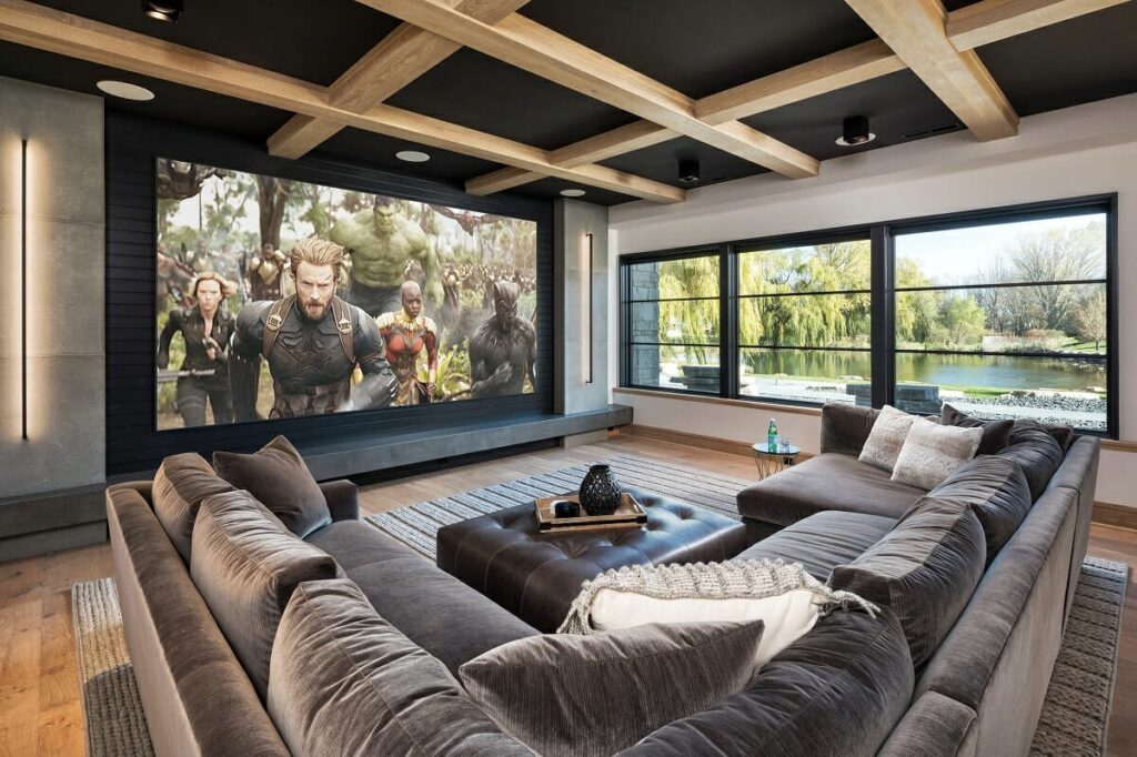 Home Theater: A cozy basement media room with a large projection screen, plush sectional sofa, and rustic wood-beamed ceiling.