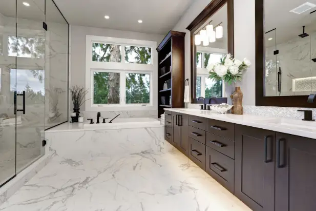 Modern white bathroom with marble floors and dark vanity cabinets