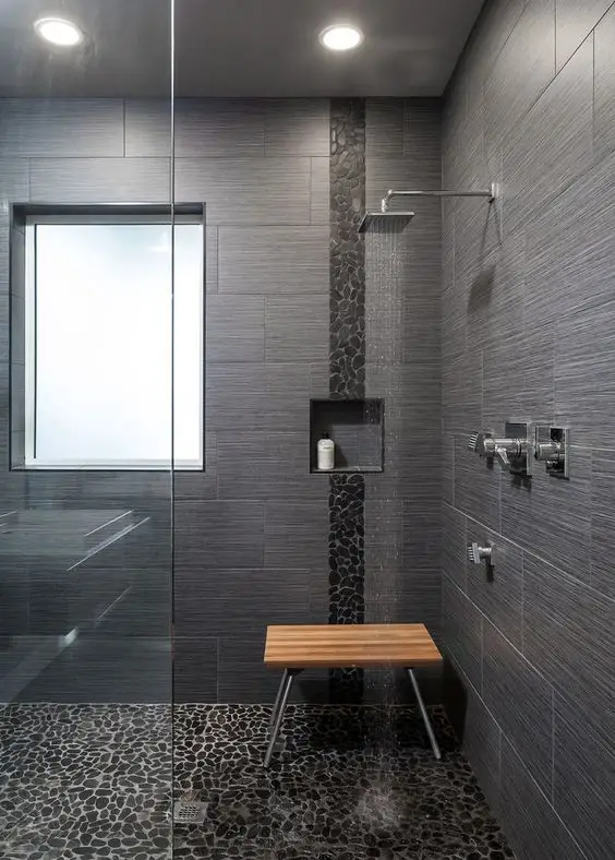 Modern gray tiled walk-in shower with window and wooden bench